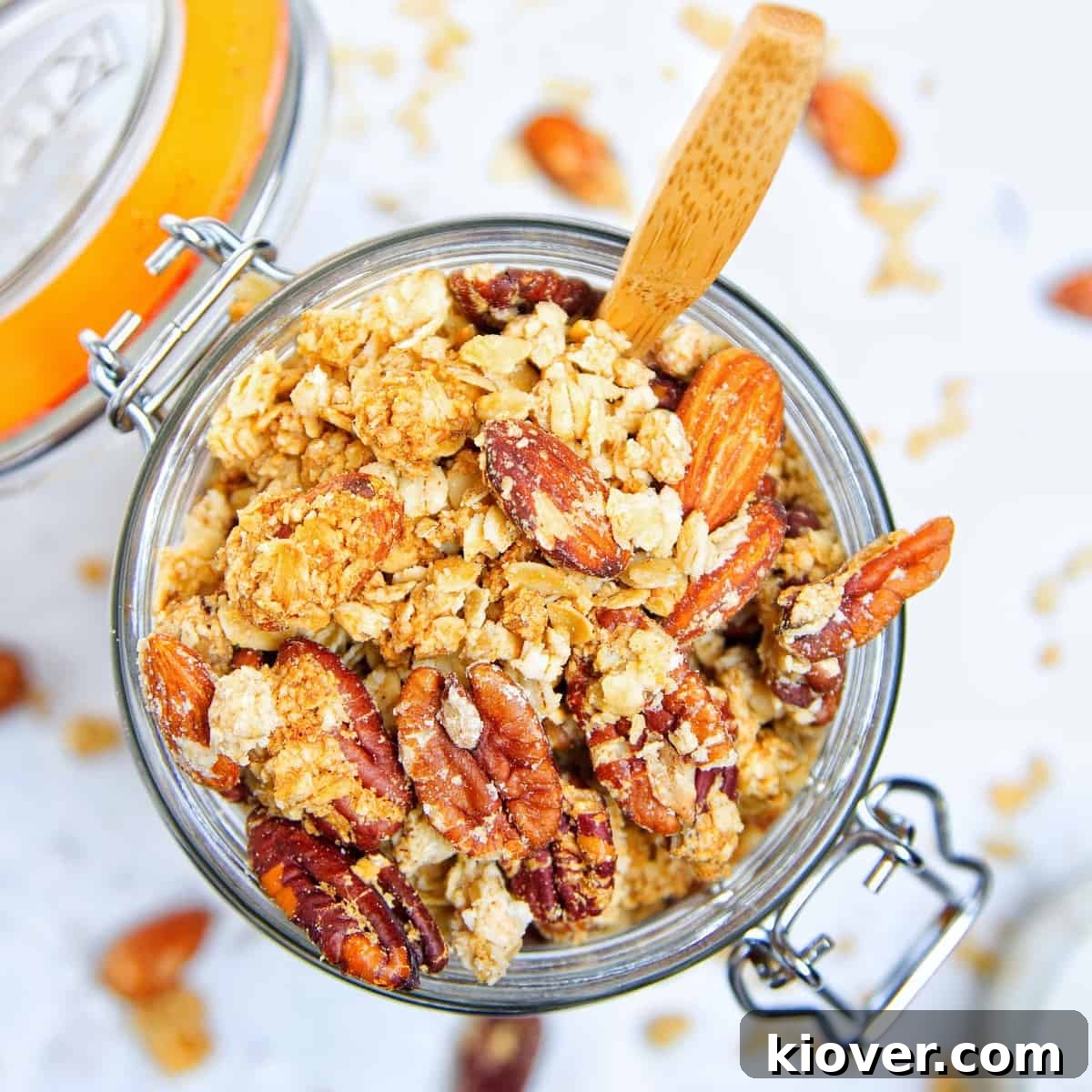 peanut butter granola in a large glass jar with wooden spoon