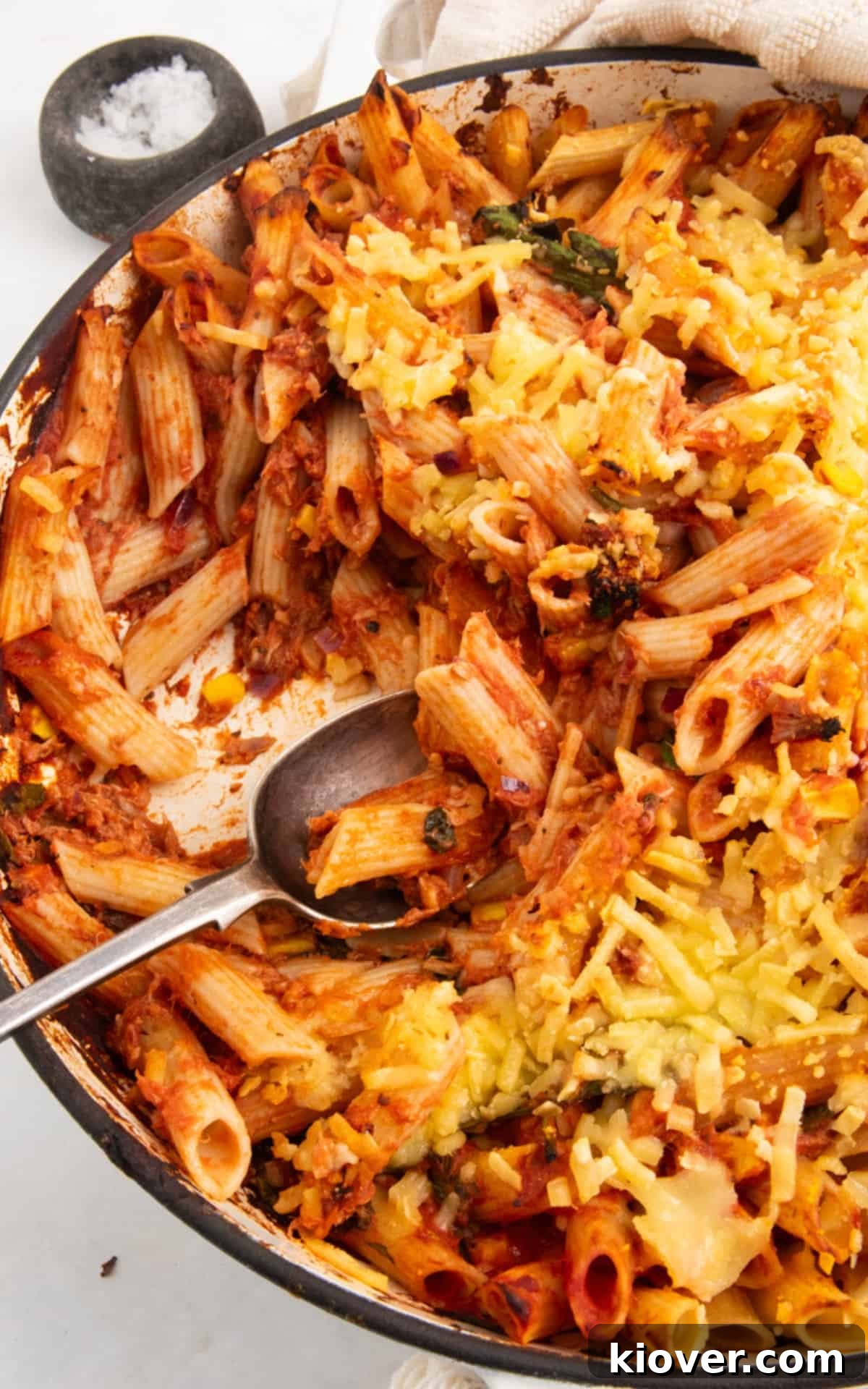 tuna pasta bake served in a white casserole dish with a spoon for serving.