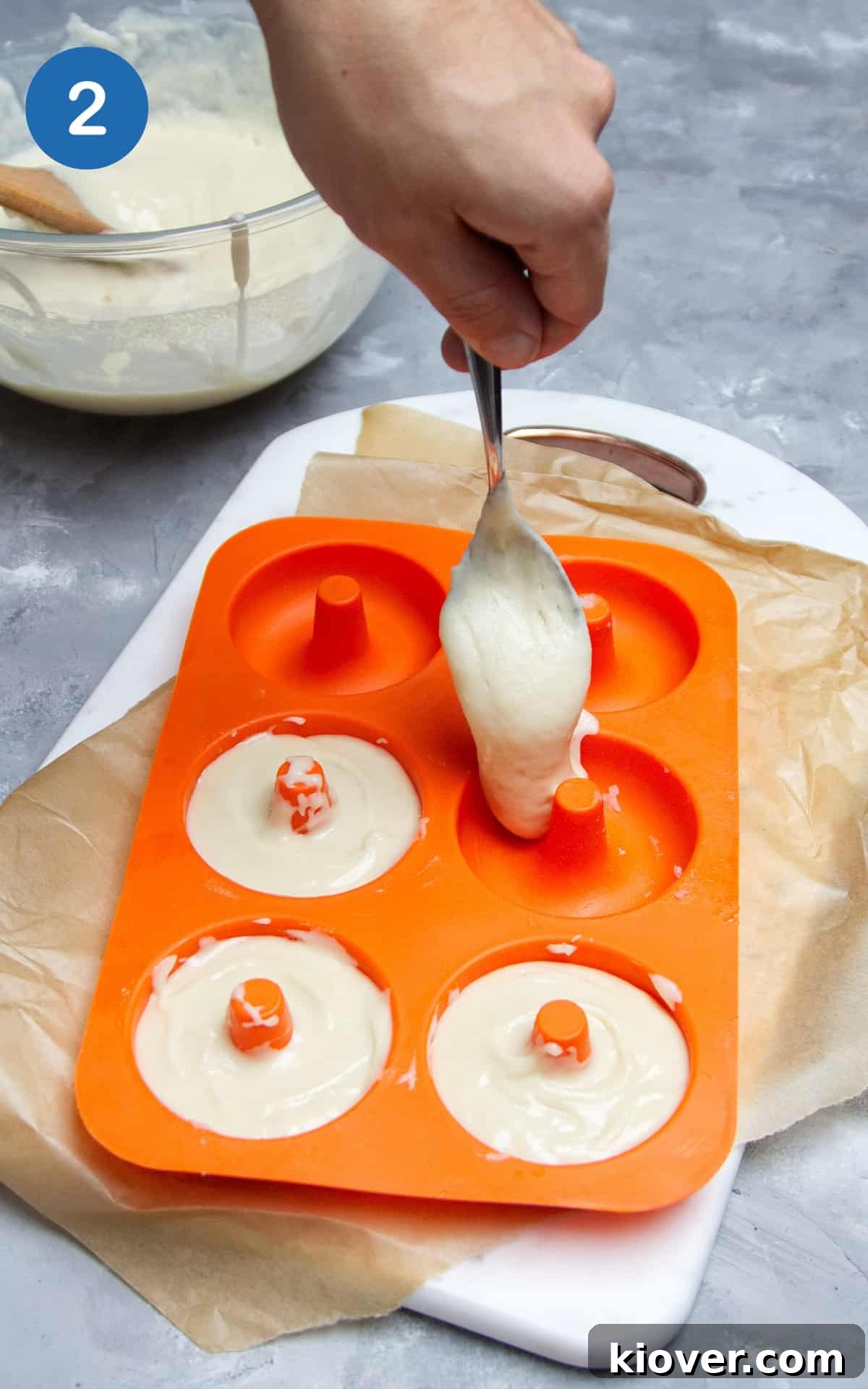 doughnut batter being transferred to orange silicone mould.