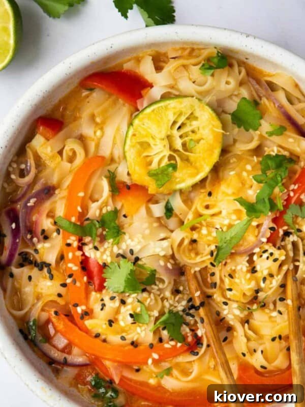 Creamy Vegan Laksa Recipe: Flavorful Plant-Based Coconut Curry Soup 10 Thai Curry Noodle Soup in a bowl with chopsticks, displayed on a white marble background with lime and coriander.