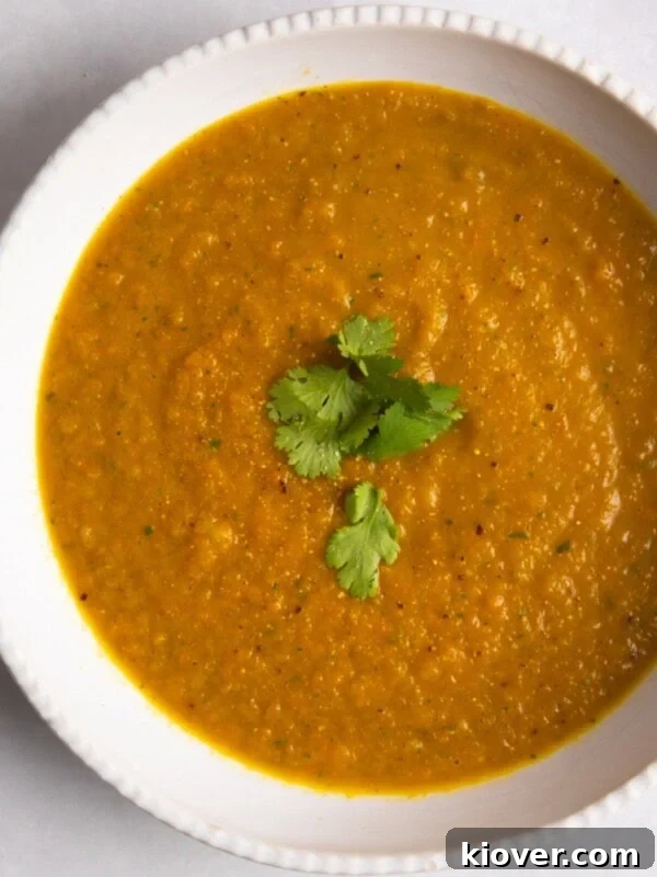 Creamy Roasted Parsnip Soup Recipe with Garlic and Thyme 11 Carrot & Coriander Soup served in a white bowl with coriander on top.