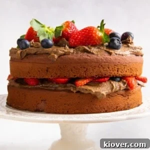 71 Top Gluten-Free Recipes for Every Meal 59 Chocolate cake topped with fresh berries on cream cake stand and white background.