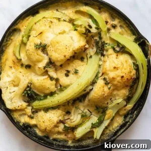 71 Top Gluten-Free Recipes for Every Meal 67 Cooked Cauliflower Cheese in black skillet pan. Pan is displayed on white marble background