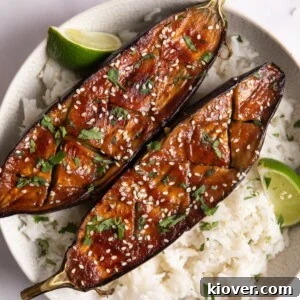 71 Top Gluten-Free Recipes for Every Meal 69 2 miso-glazed aubergines on a bed of white rice with lime wedges. The white bowl is on a white surface.
