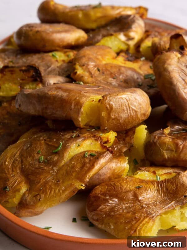 Crispy Air Fryer Jacket Potato Recipe for Perfect Baked Potatoes 7 close up of smashed potatoes on white plate with orange edge.
