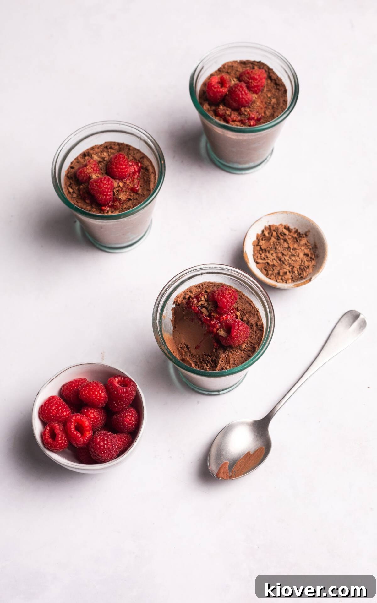 Creamy Vegan Chocolate Mousse Recipe for Decadent Desserts 8 vegan mousse with chocolate and raspberries in glass cups.