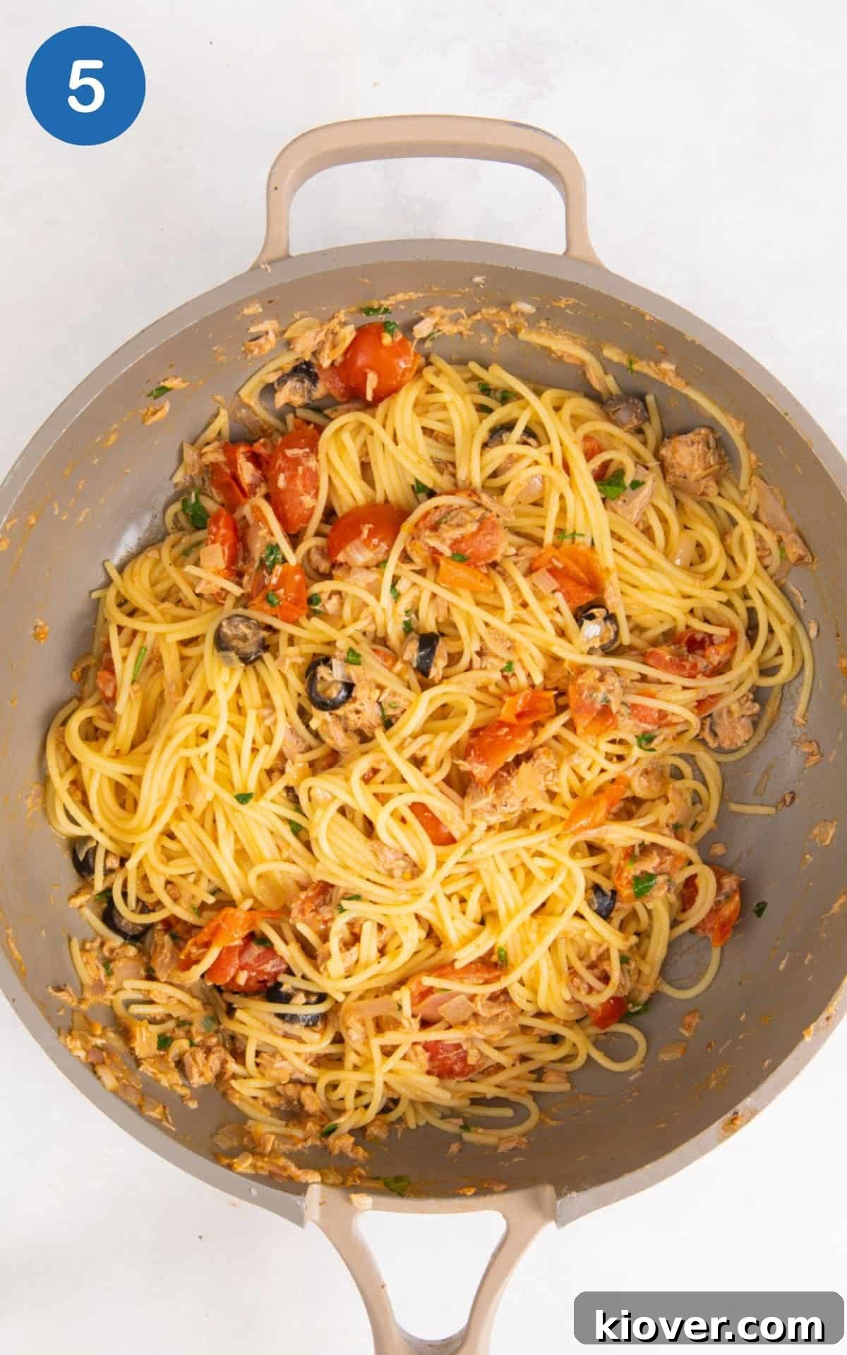 adding pasta to the pan with tuna and vegetables.