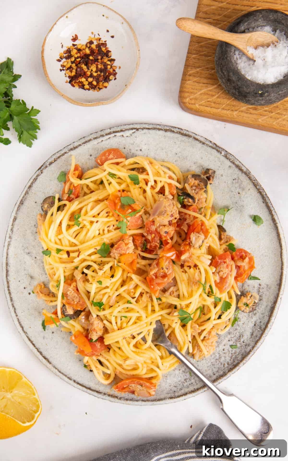 pasta with tuna and vegetables topped with chilli flakes and fresh parsley.