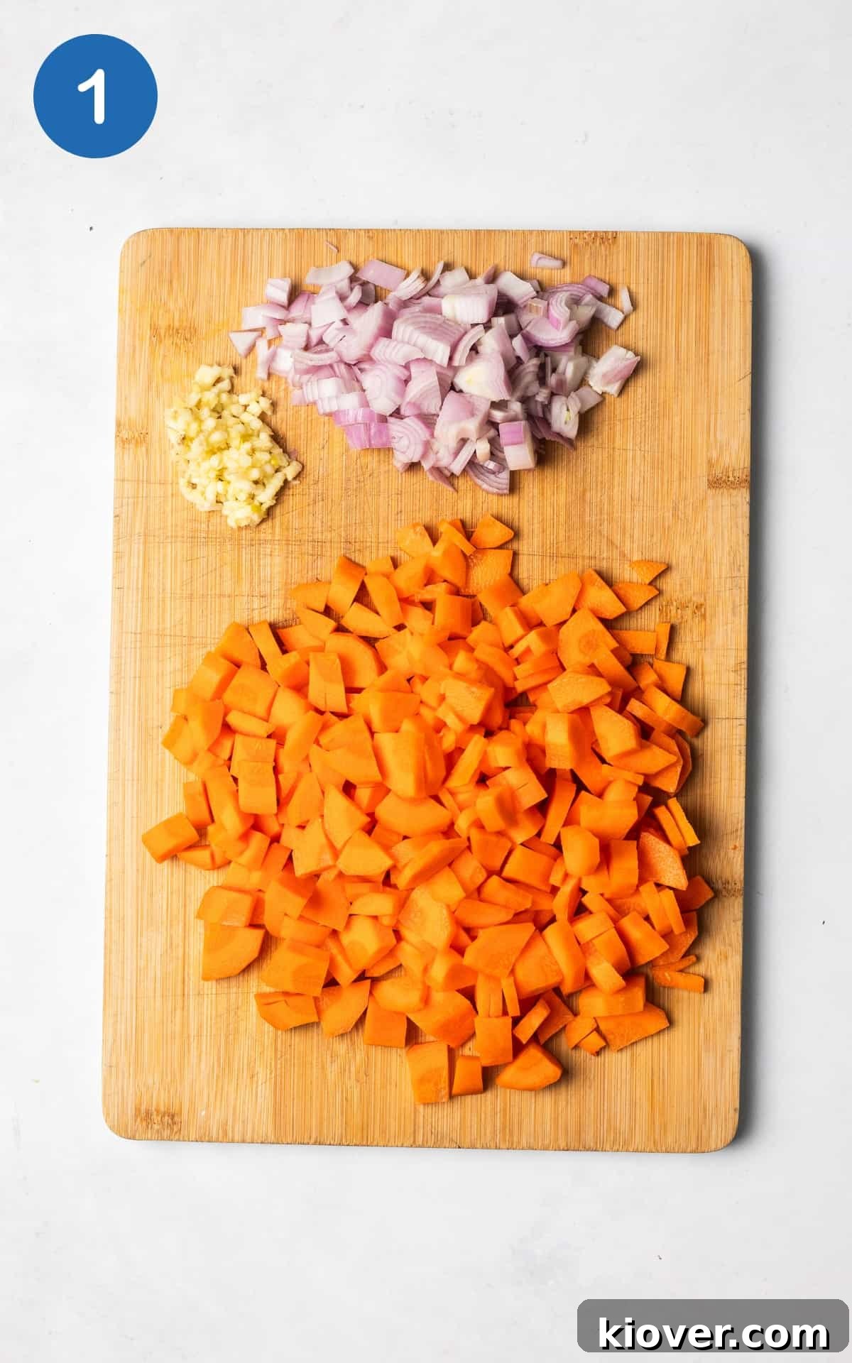 Hearty Carrot and Red Lentil Soup with Warm Spices 4 carrots, garlic and shallots on a wooden cutting board.