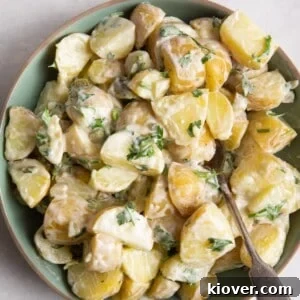 43 Gluten-Free Vegan Recipes for Everyday Meals and Desserts 41 potato salad in green bowl with beige rim. Bowl is on white surface.