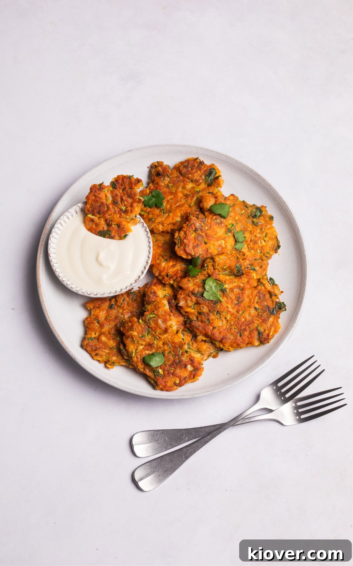 Crispy Courgette Fritters with Garlic Yogurt Dip 10 zucchini fritters served on a plate with coconut yoghurt.