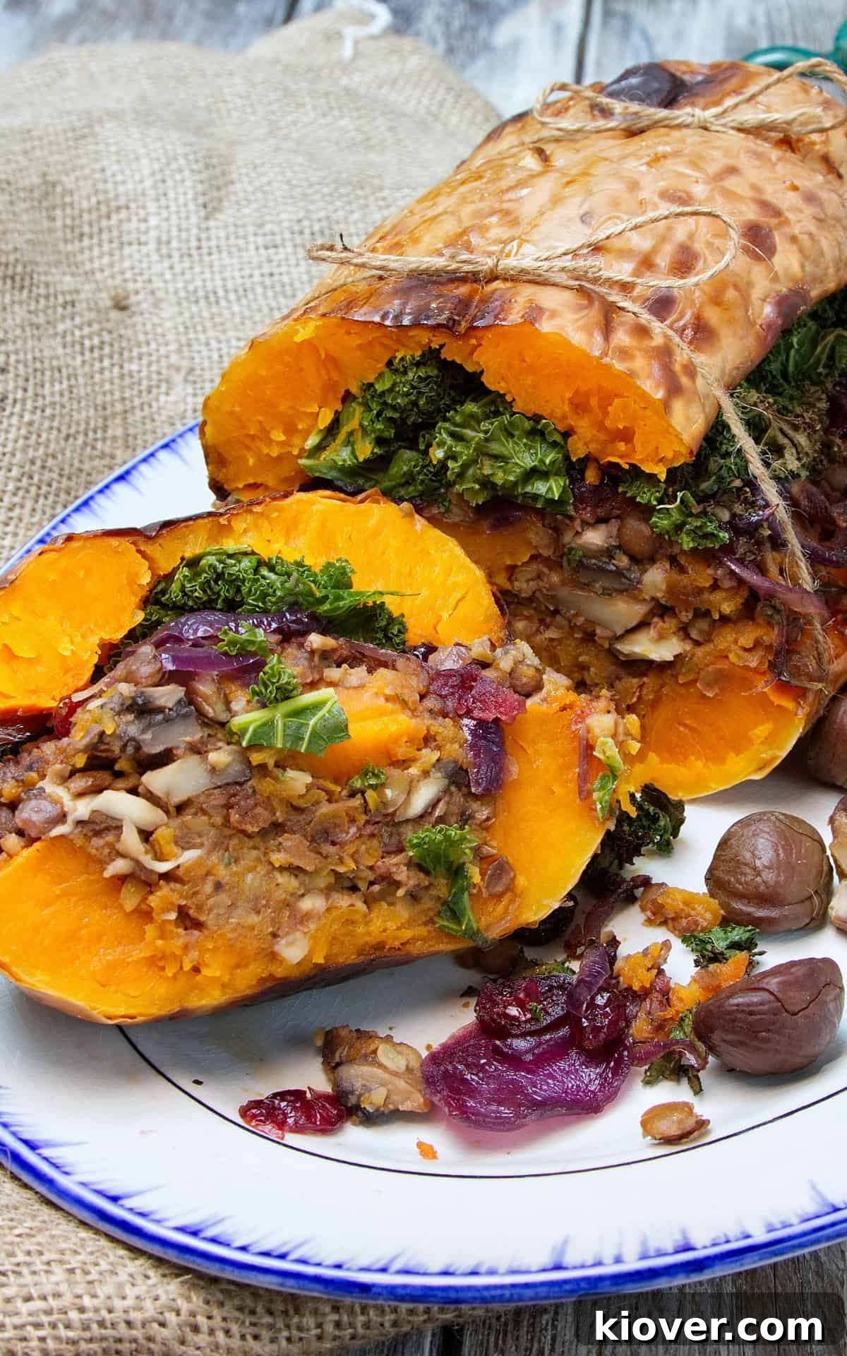 roasted stuffed butternut squash on a large white plate sliced open.