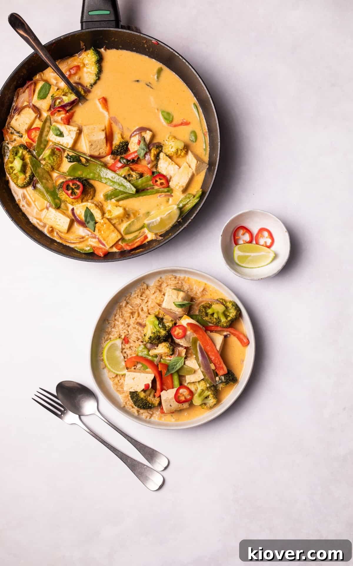 Authentic Vegan Thai Curry Recipe with Creamy Coconut Sauce 8 Vegetables, tofu and rice on a plate next to a pan with Vegan Thai Curry.
