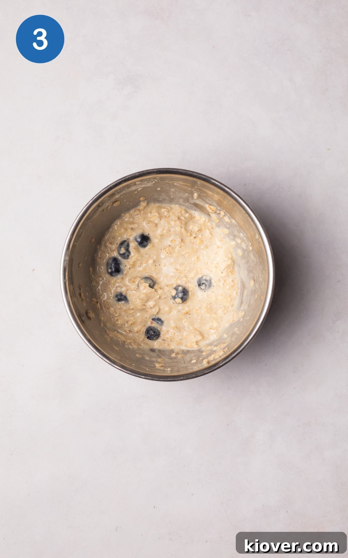 Creamy Baked Oats Recipe for Breakfast and Meal Prep 6 Blueberries added to the mixture in a bowl.