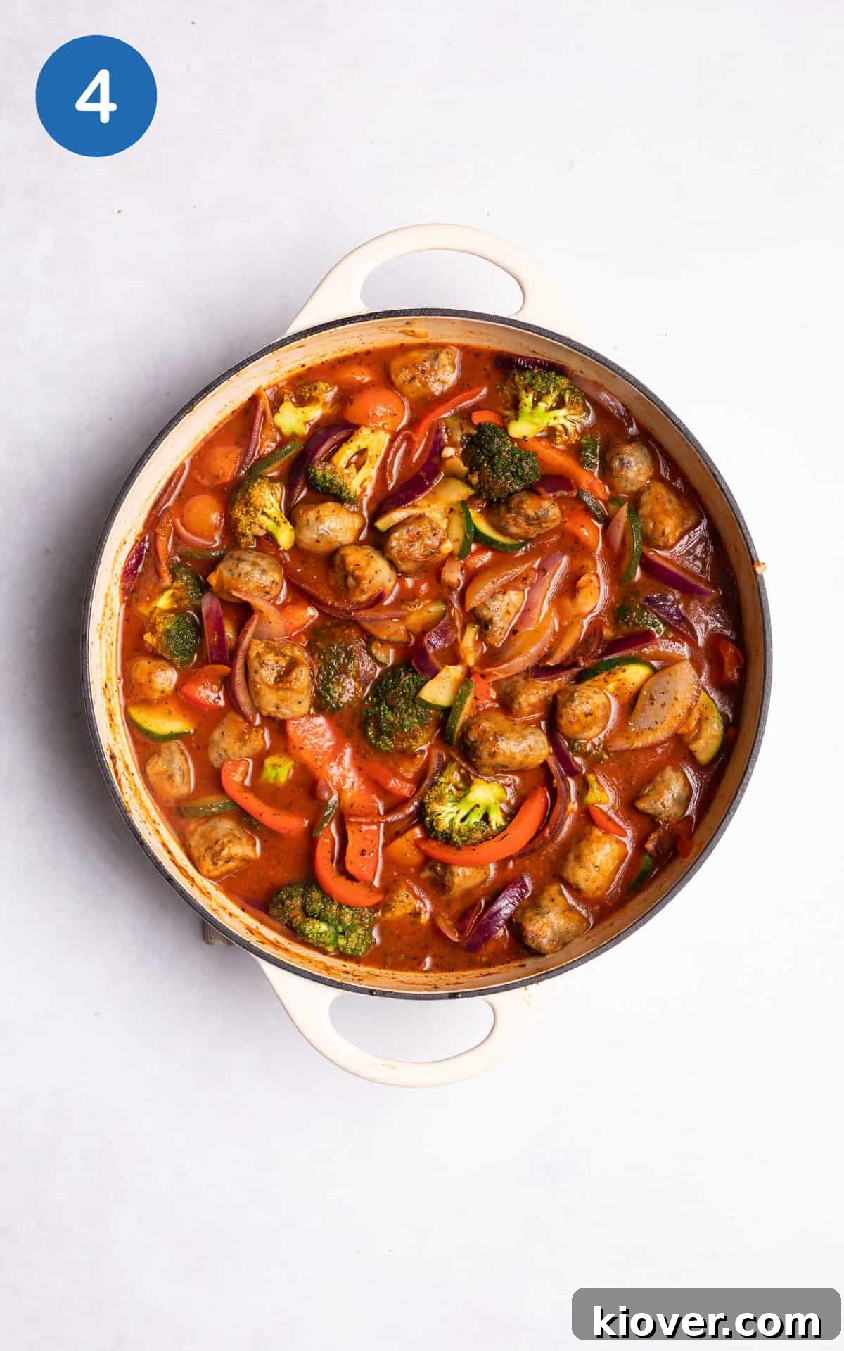 adding passata and vegetable stock to the pan with the vegetables and sausages.