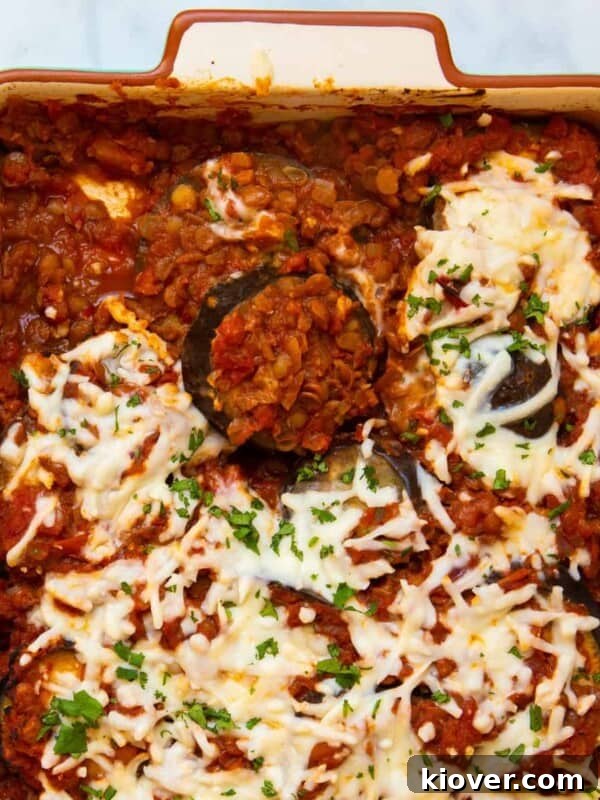 aubergine bake in a baking dish topped with parsley served on a marble background.