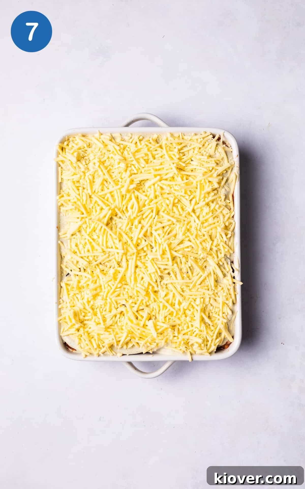 Vegan Greek Moussaka Recipe: Creamy Eggplant and Lentil Bake 10 adding grated cheese on top of vegan moussaka.