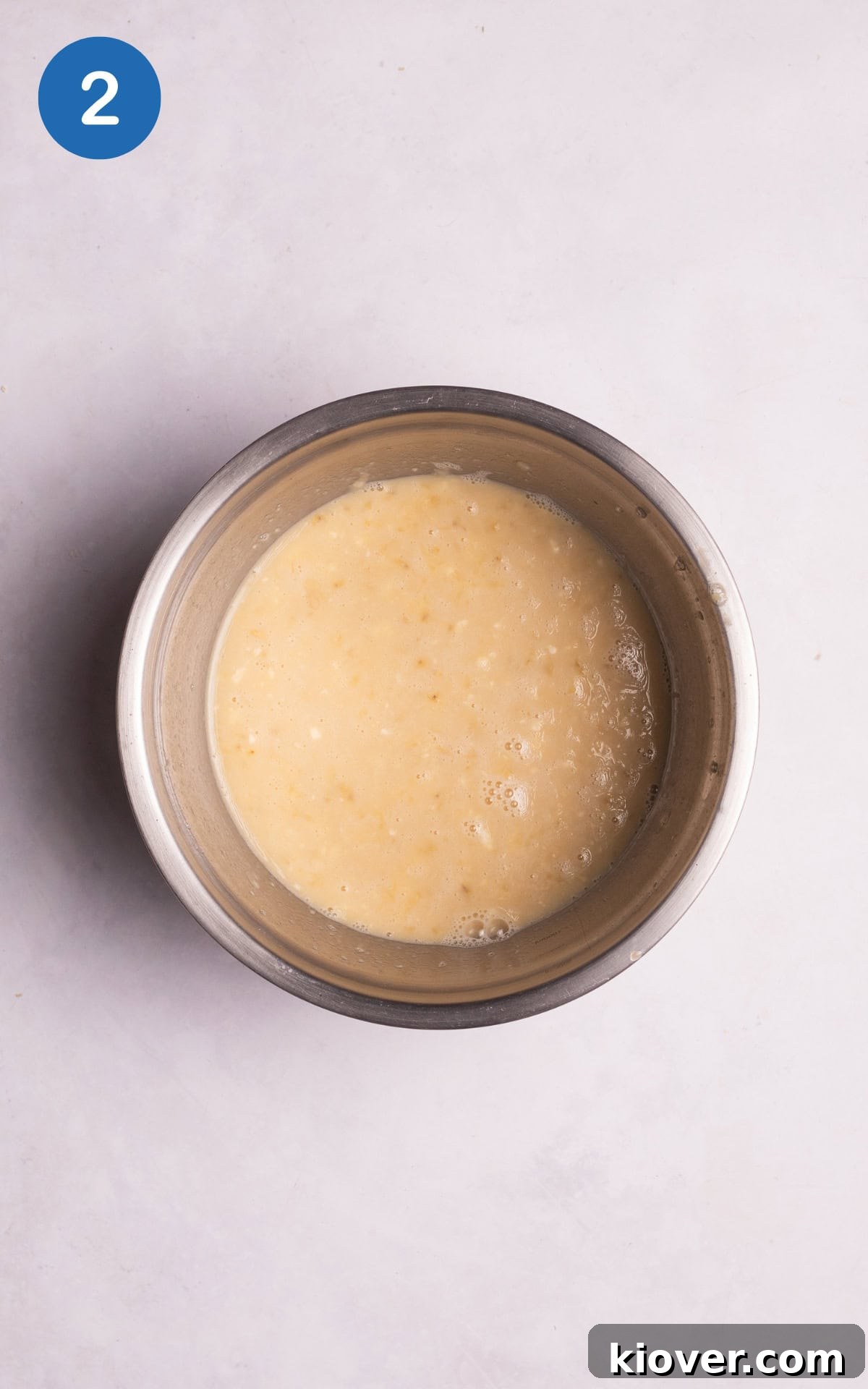 Mashed banana combined with the vanilla extract, maple syrup, and milk in a bowl.