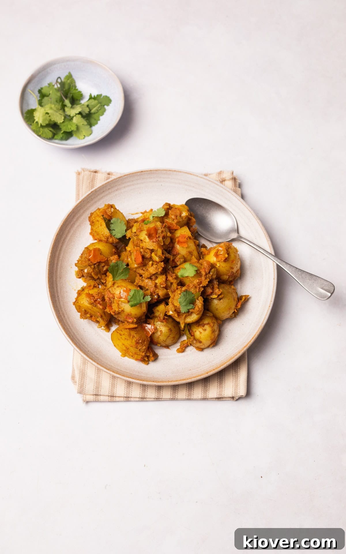 Bombay Aloo (Bombay Potatoes) served on a plate with fresh corriander.