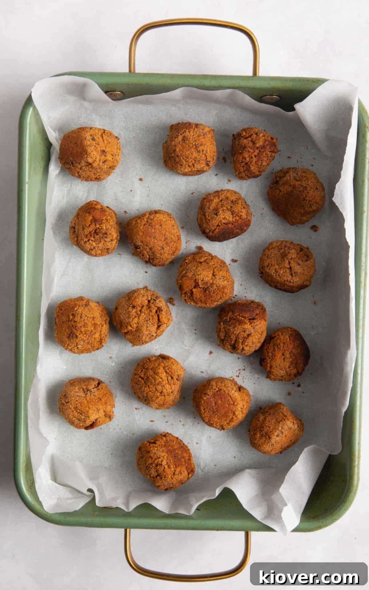 meatballs in green baking dish on white surface.