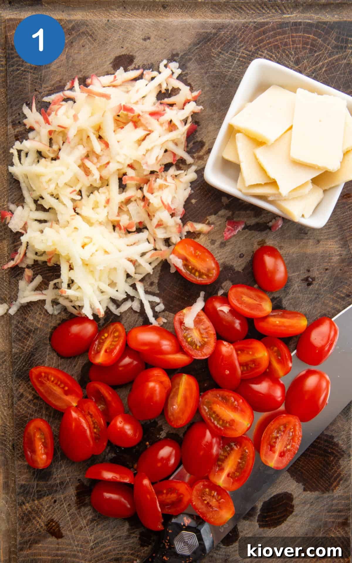 cherry tomatoes, grated apple and parmesan cheese on a wooden cutting board.