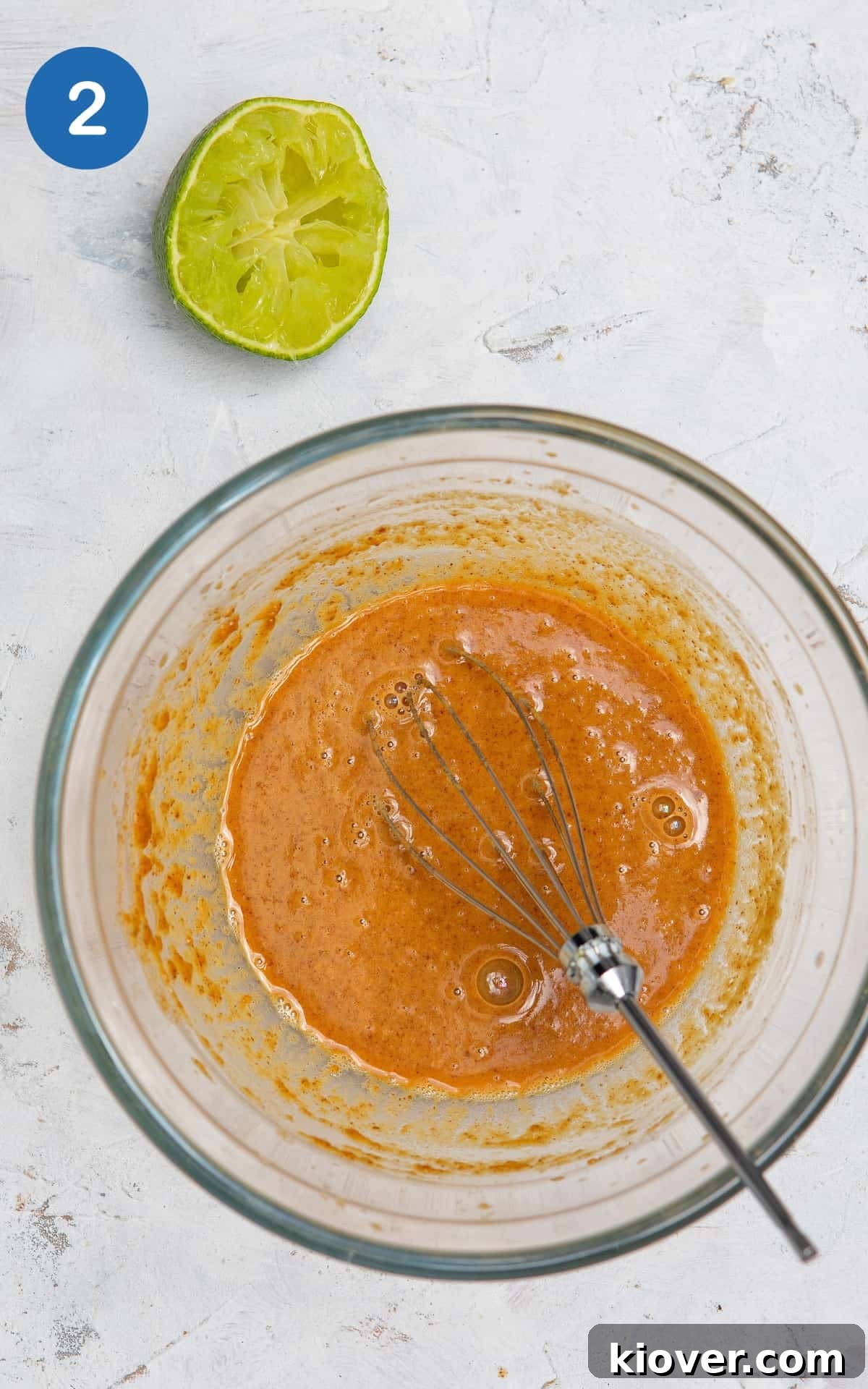 peanut butter, tamari, sesame oil and lime sauce in a bowl on white marble background.