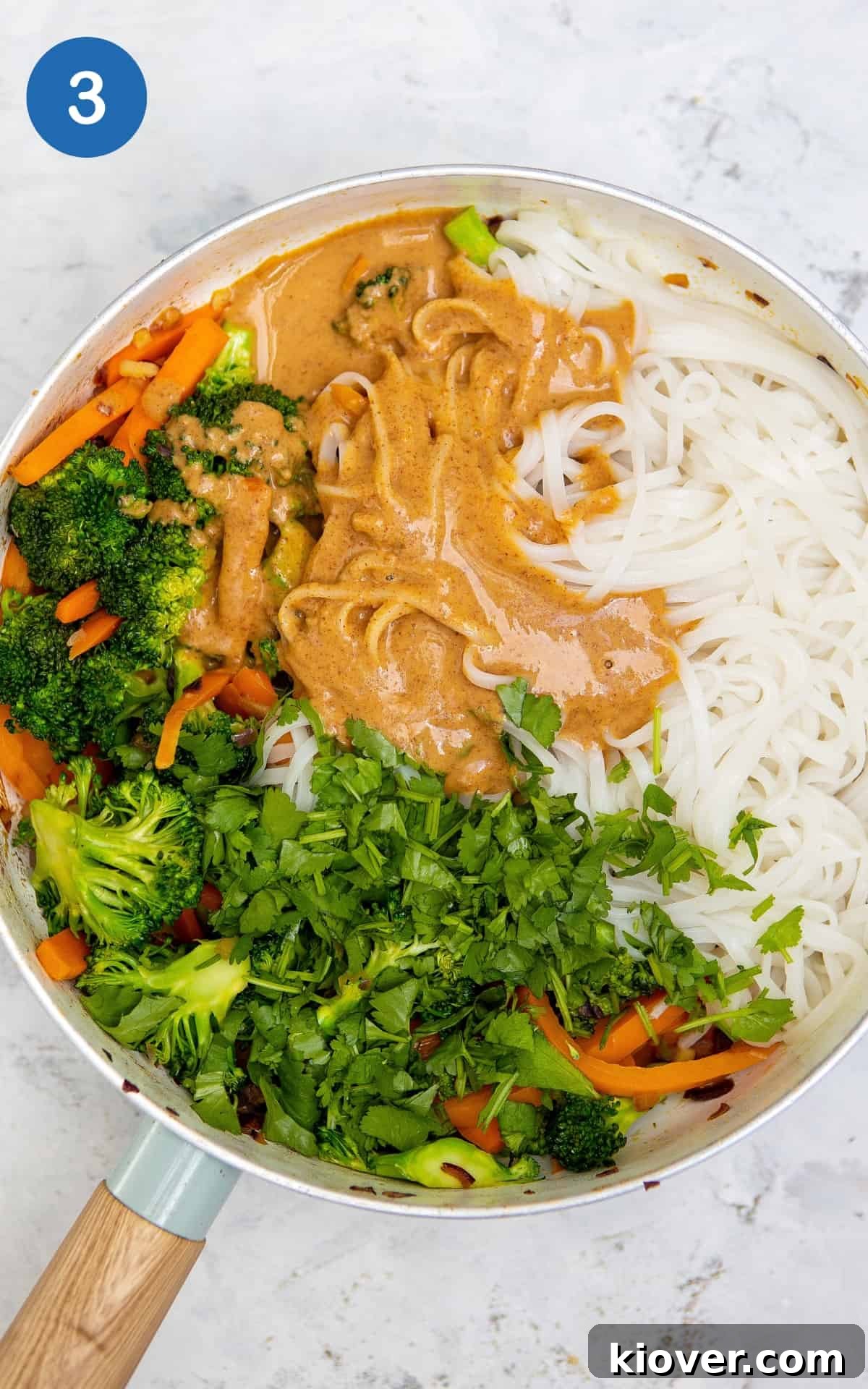 peanut butter noodles with vegetables in a frying pan.