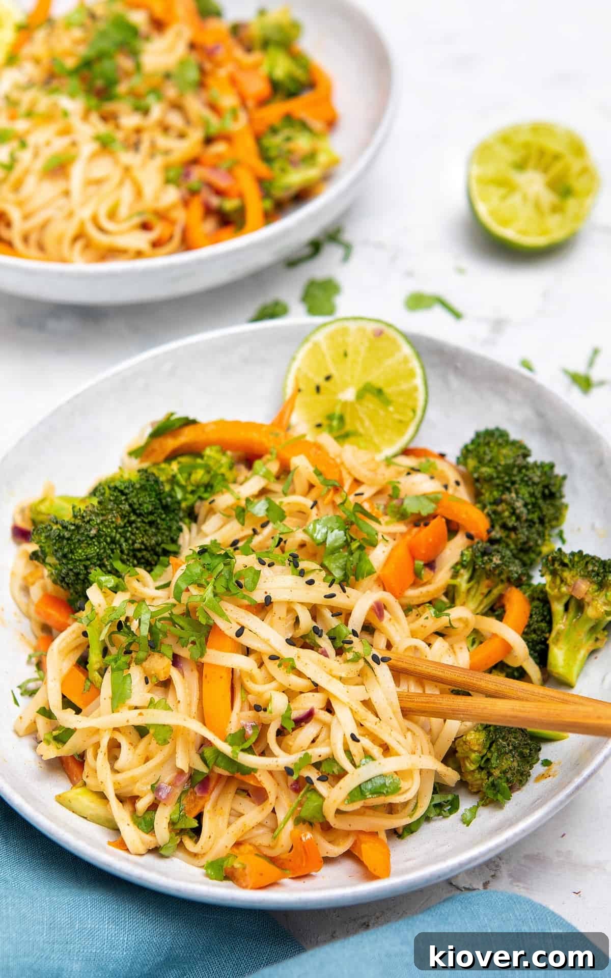 peanut butter noodles with two wooden chopsticks in a white bowl.