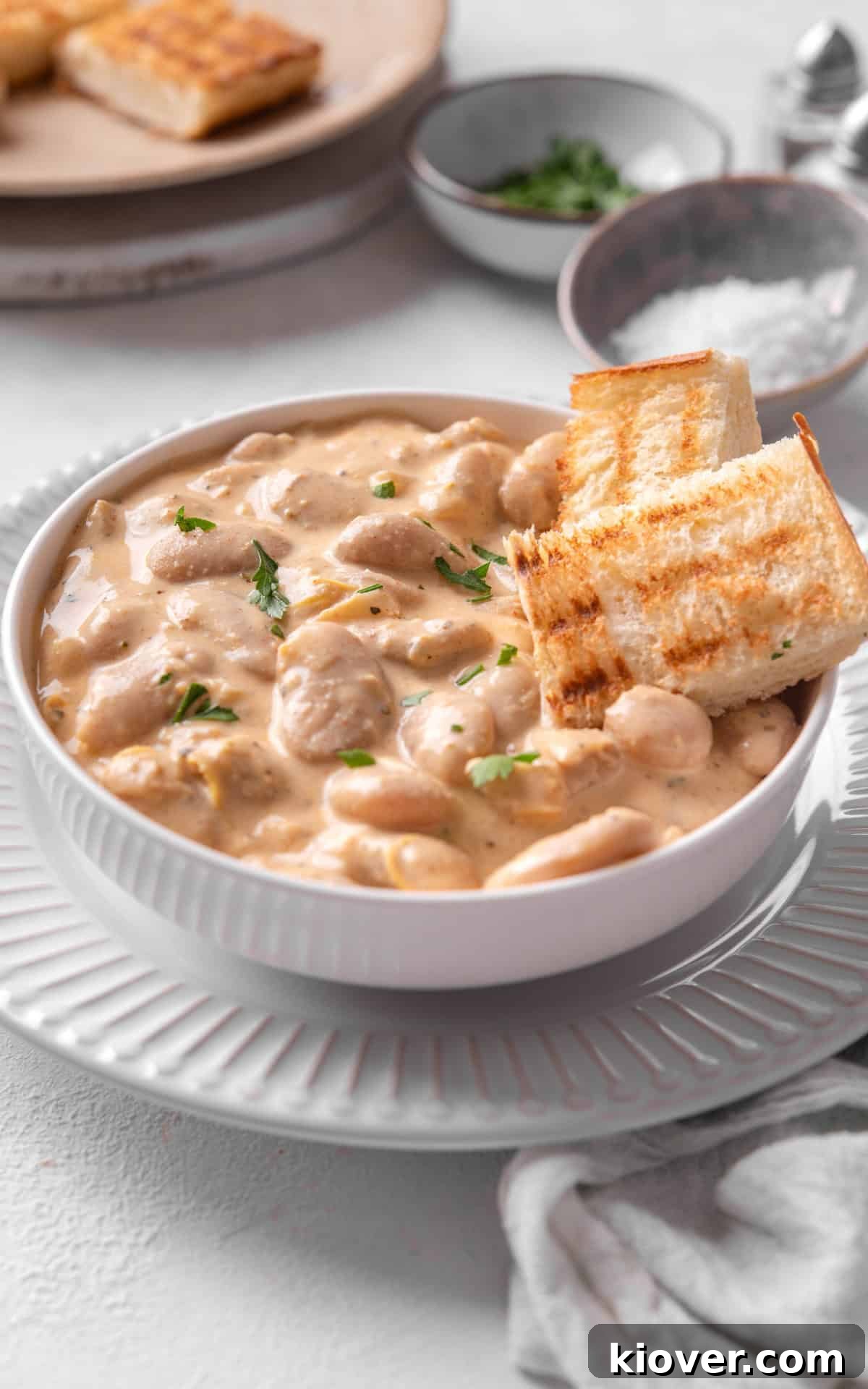 Creamy Butterbean Stew with Garlic and Herbs 9 Creamy Lemon Butterbeans served in a white bowl with bread.