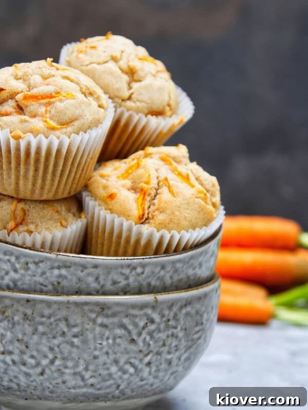 Vegan Carrot Cake Cupcakes in a bowl with carrots in the background.