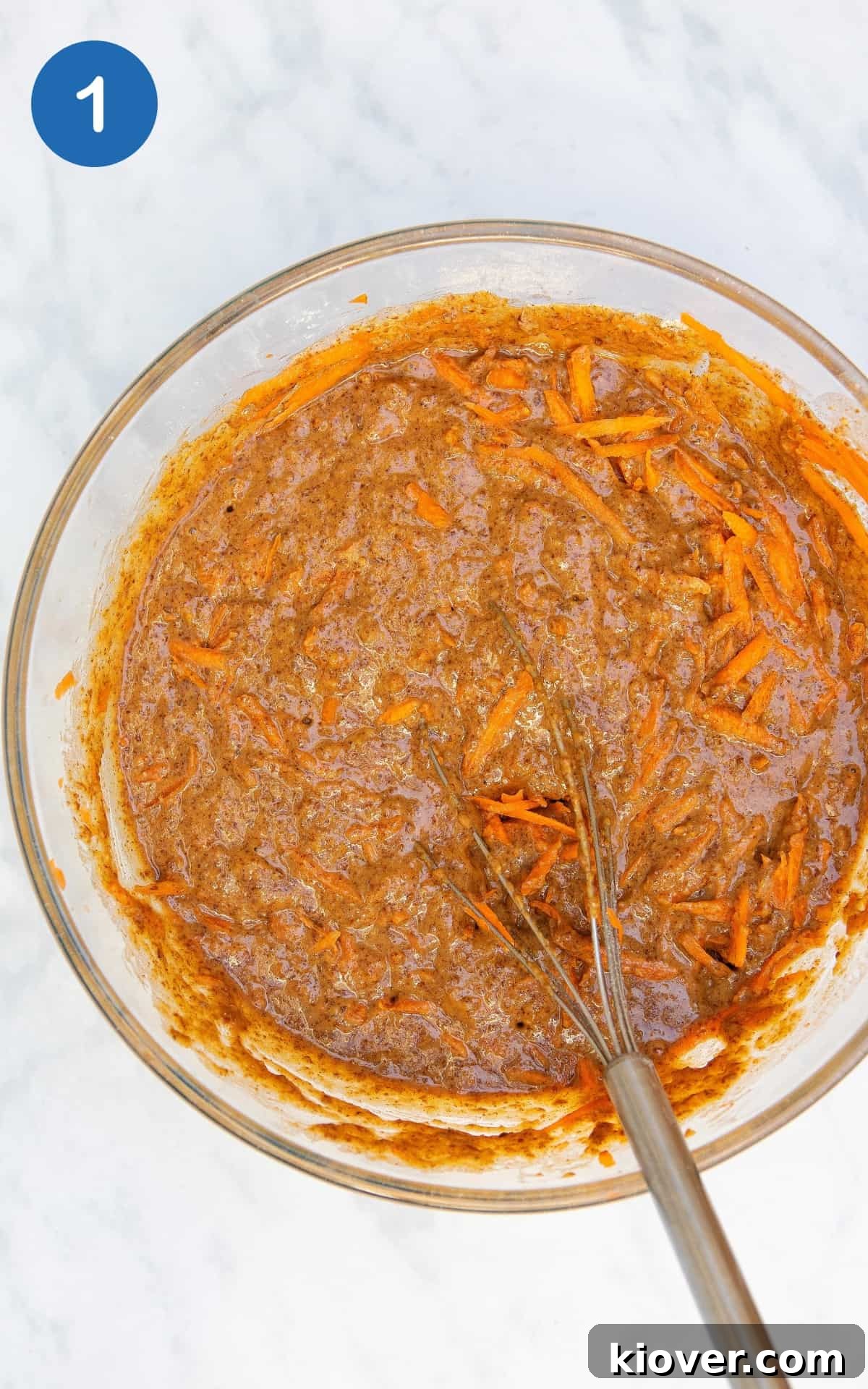Carrot cake batter in a clear pyrex bowl with whisk.