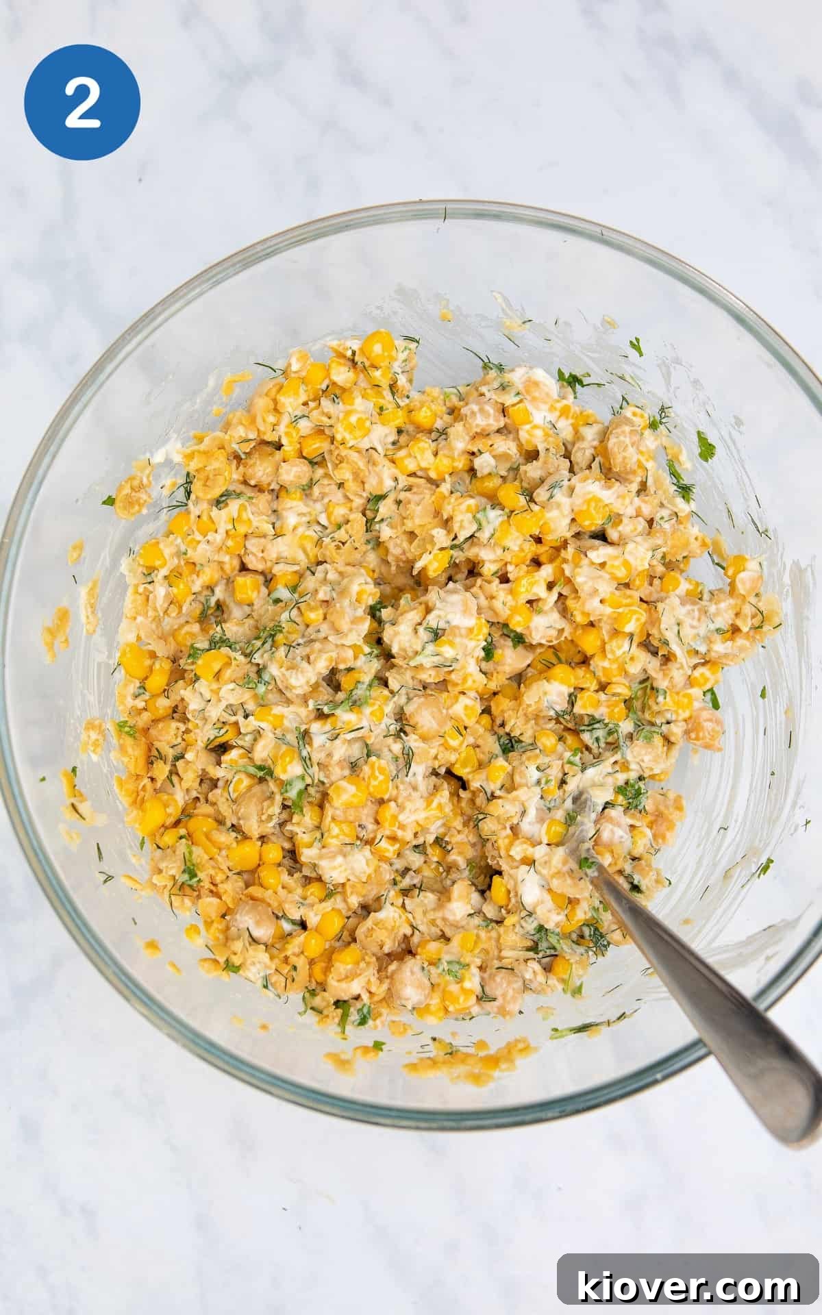 Chickpea and Tuna Salad Recipe for Meal Prep 5 all chickpea tuna salad ingredients mixed together in a glass bowl on a white surface.