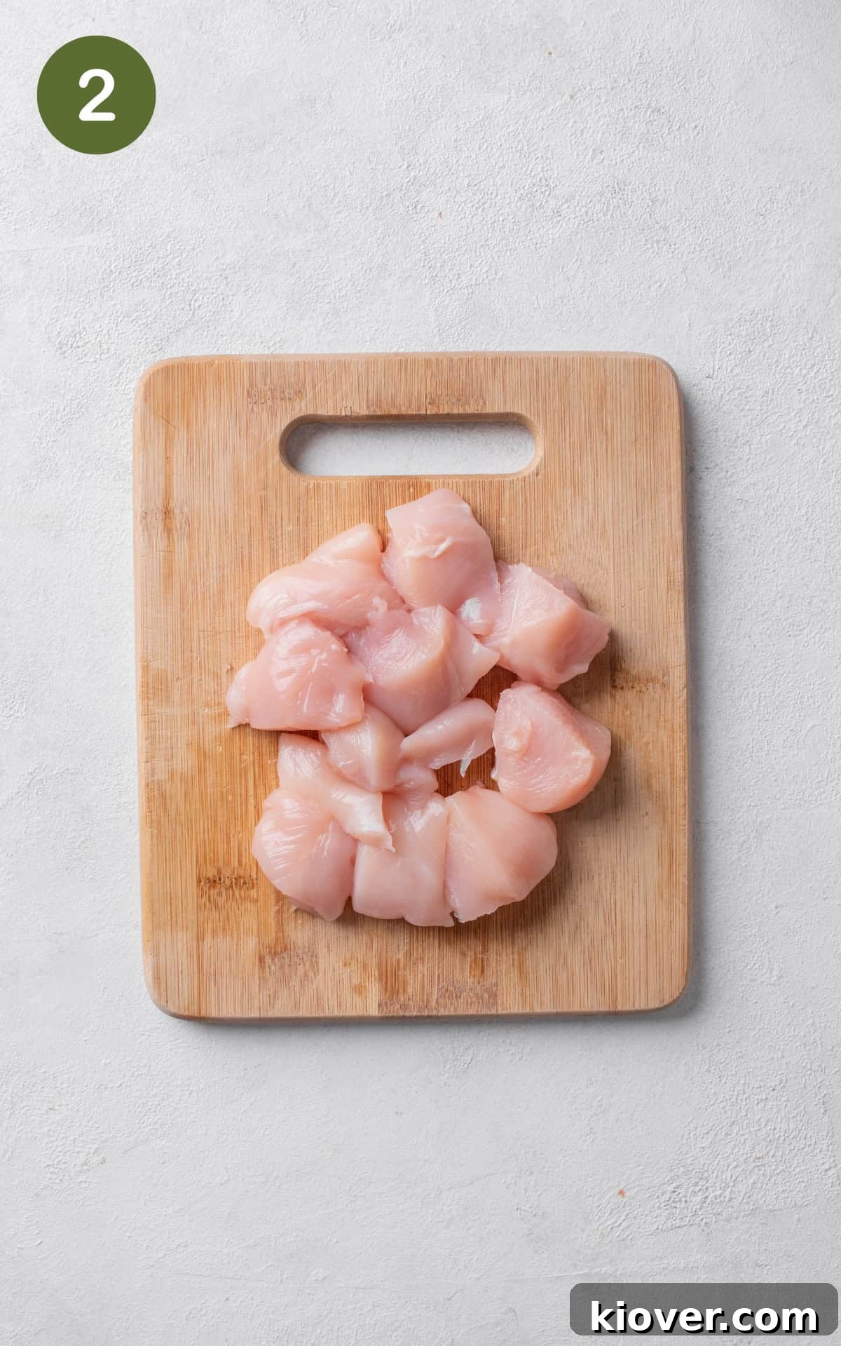 chicken breast cut into bite sized pieces on a wooden cutting board.