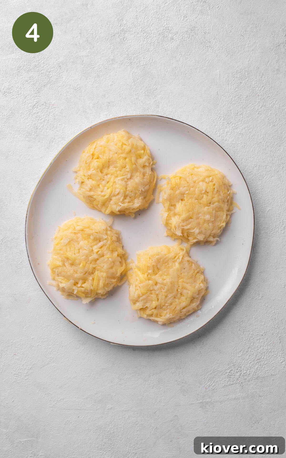Crispy Swiss Potato Rösti Recipe — Golden Hash Brown Style 7 potatoes shaped into four rostis on white plate.