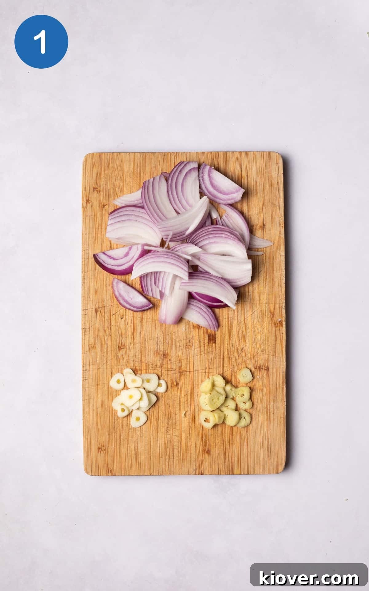 onion, garlic and ginger on a wooden cutting board.