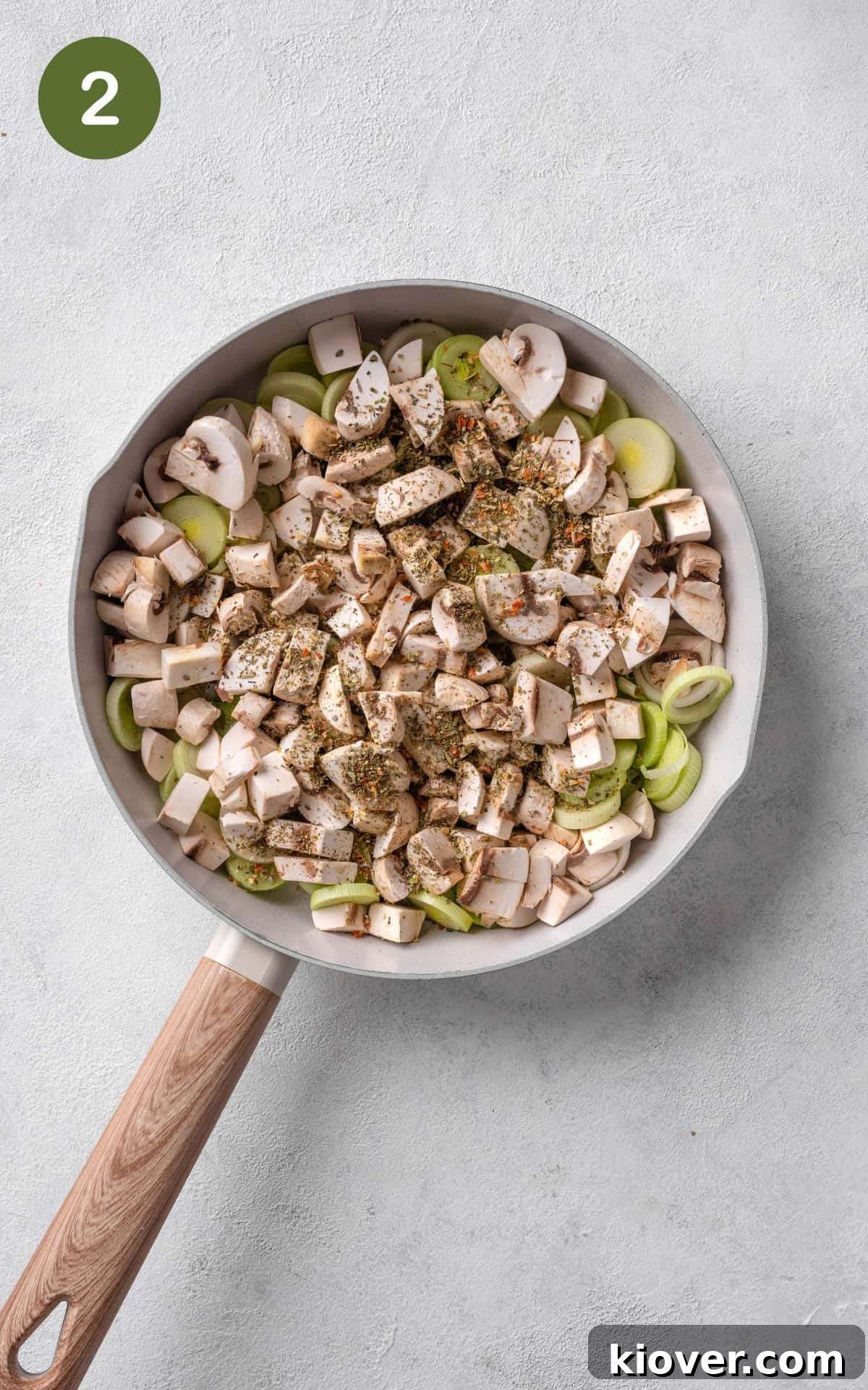 Classic Chicken and Leek Pie Recipe for Comforting Dinner 5 cooking leeks, mushrooms, garlic, and Italian herbs on butter in a frying pan.