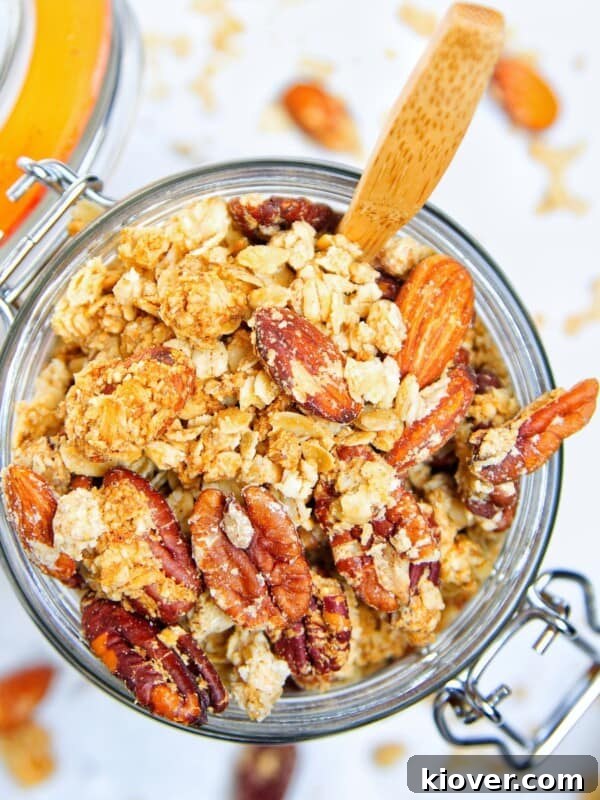 peanut butter granola in a large glass jar with wooden spoon