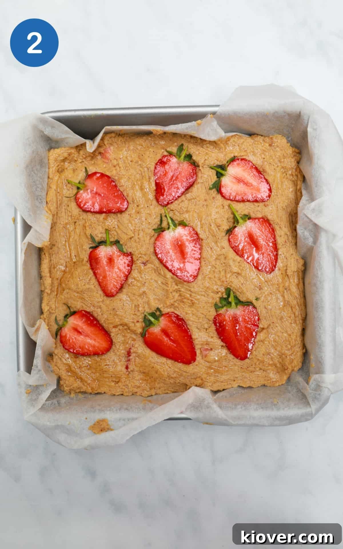 Peanut Butter Blondies mixture in a baking tray with strawberries on top.