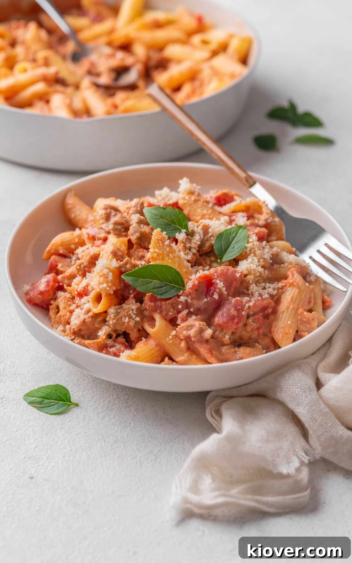 sausage pasta garnished with fresh basil leaves.