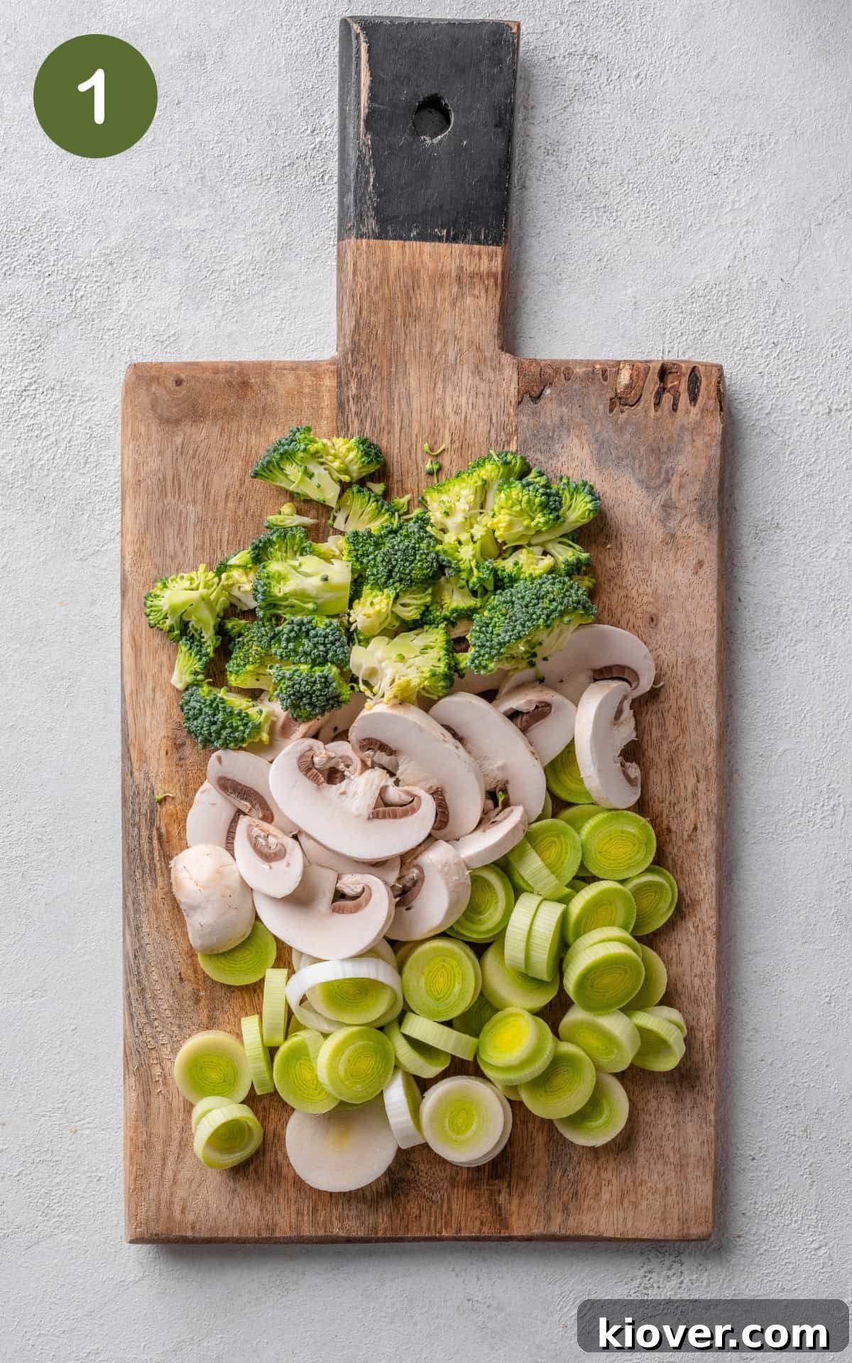 Creamy Chicken Pasta Bake with Melty Cheese and Herbs 4 leek, mushrooms and broccoli on a wooden cutting board.
