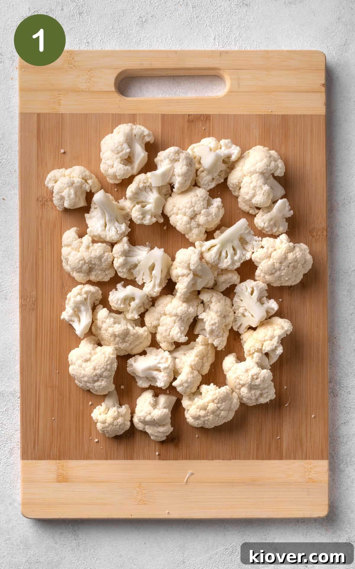 cauliflower florets on a wooden cutting board.