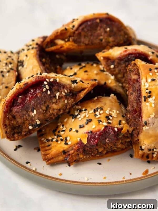 Sausage Tray Bake Recipe with Roasted Veggies and Herb Gravy 10 homemade lentil and walnut sausage rolls on a stoneware plate garnished with sesame seeds.