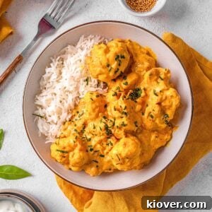 cauliflower curry served in a white bowl with rice.