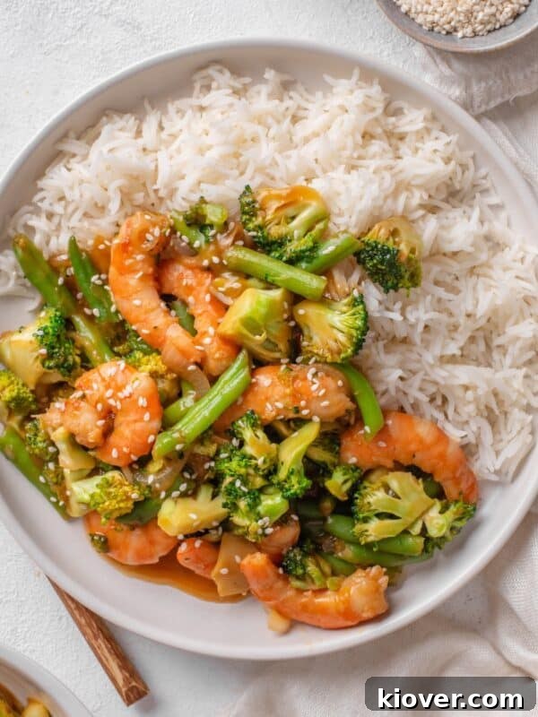 prawn stir fry served on a white plate with white rice.