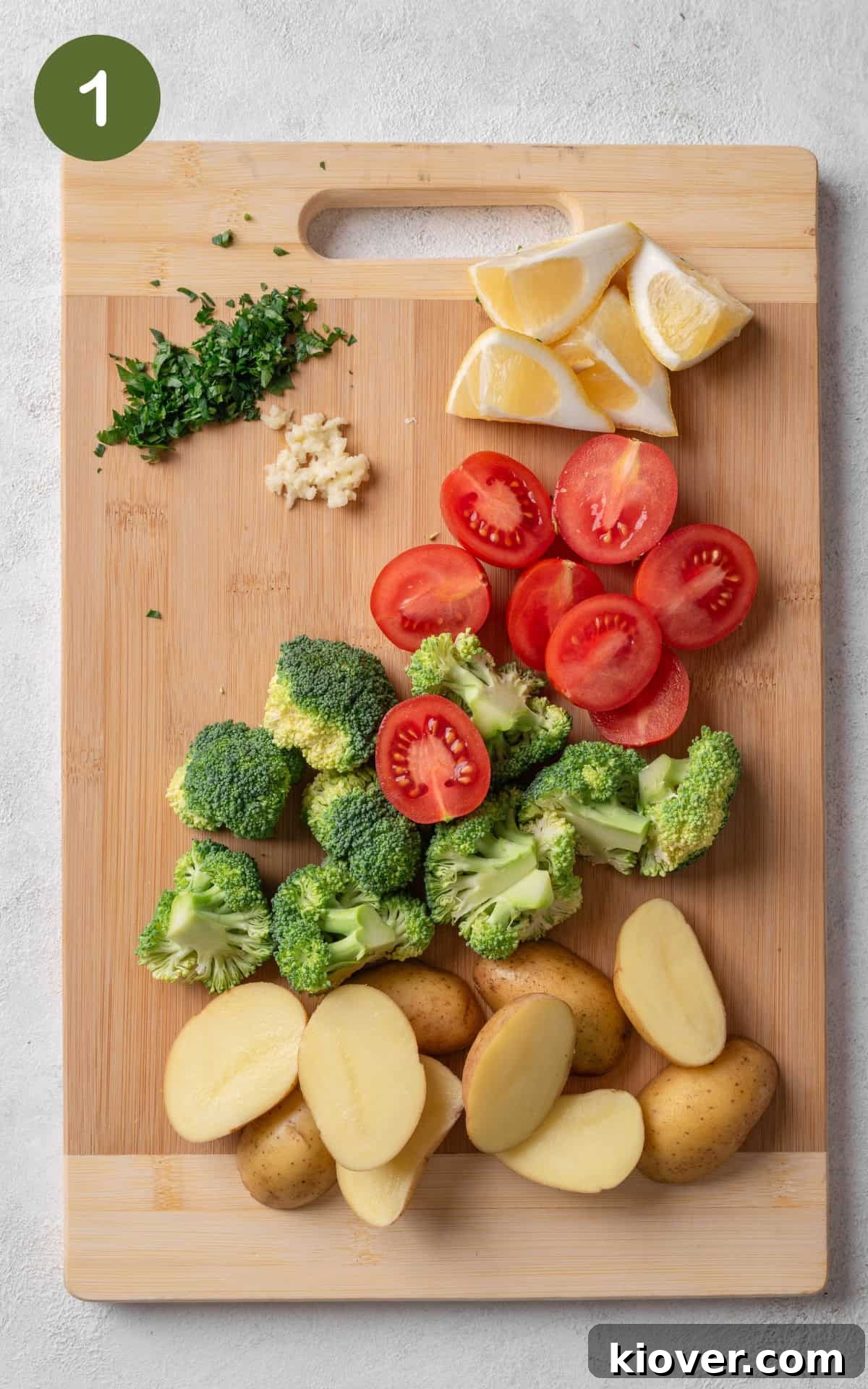 Flavorful Salmon Tray Bake with Lemon, Garlic, and Roasted Veggies 4 vegetables on a wooden cutting board.