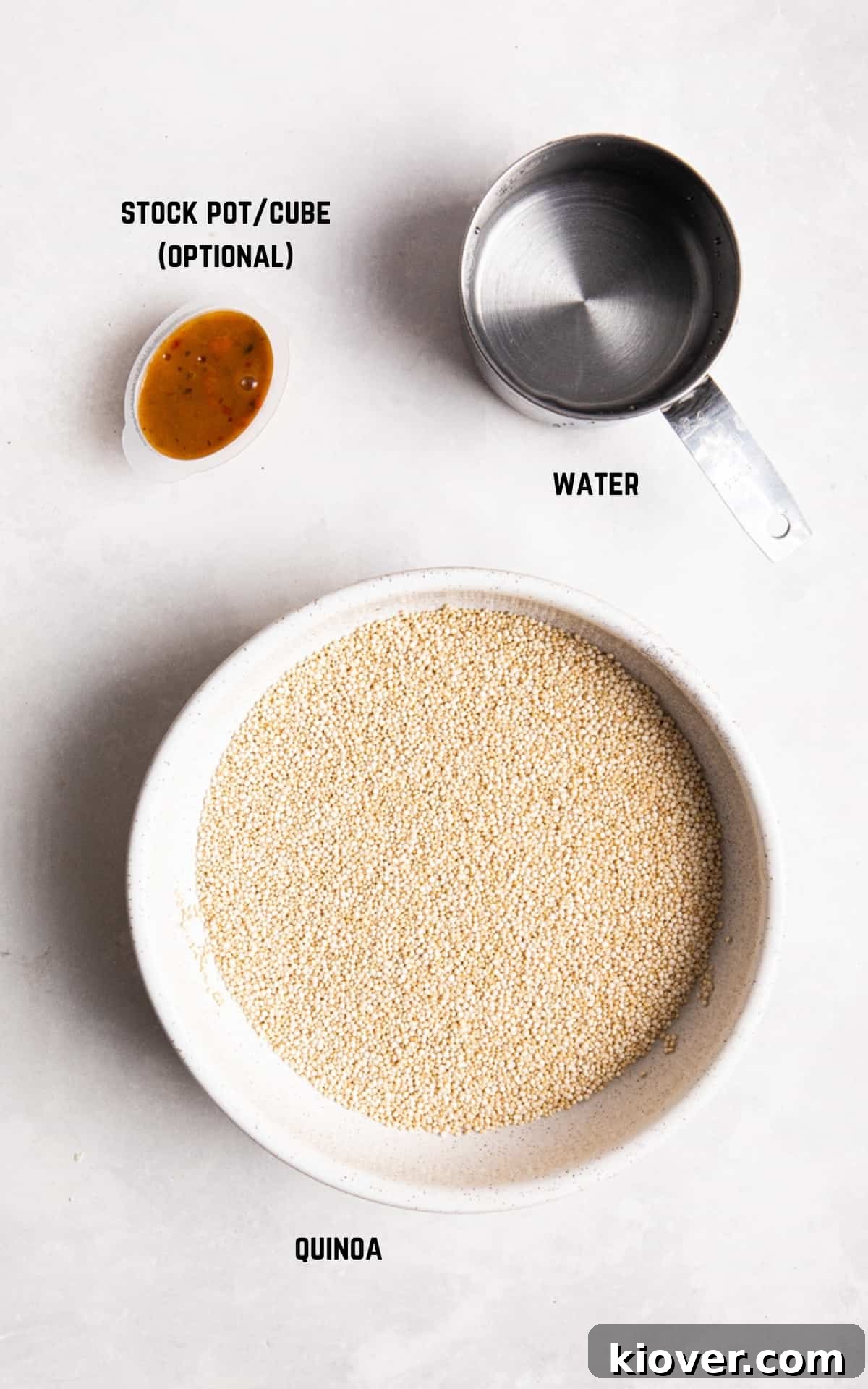 quinoa, water and stock pot/cube on a table.