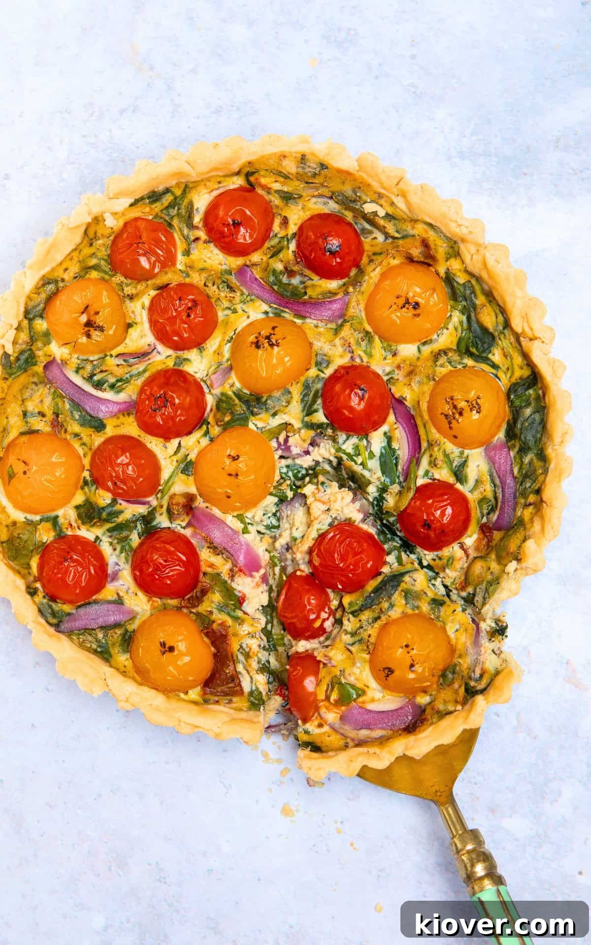 overhead shot of home made gluten free quiche on grey marbled surface with slice being taken out of it.