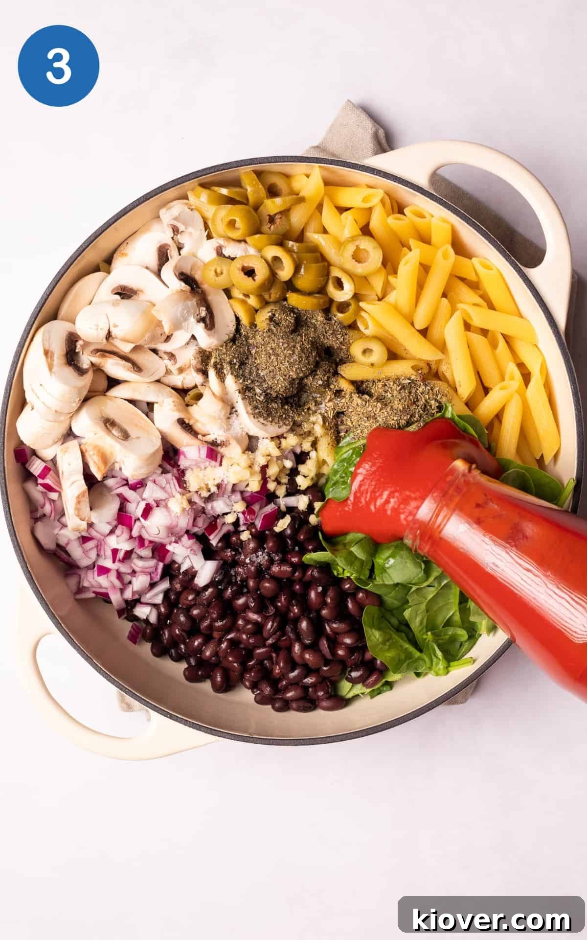 Vegetables and pasta in a pot with passata on top.
