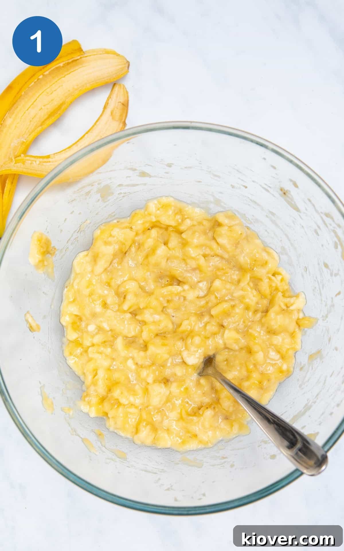 Banana Breakfast Bars with Oats and Nuts receita 4 mashed banana in a glass bowl with a fork.
