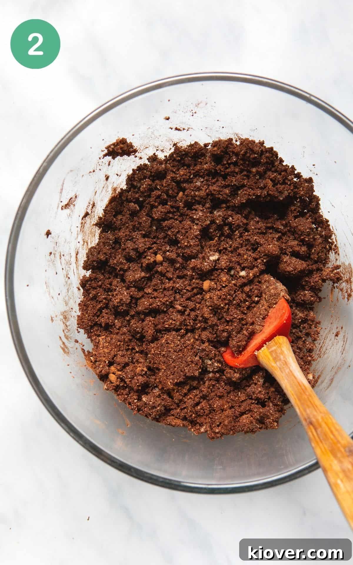 Instructional photo of a bowl having the ingredients for the crust mixed together in a glass bowl.
